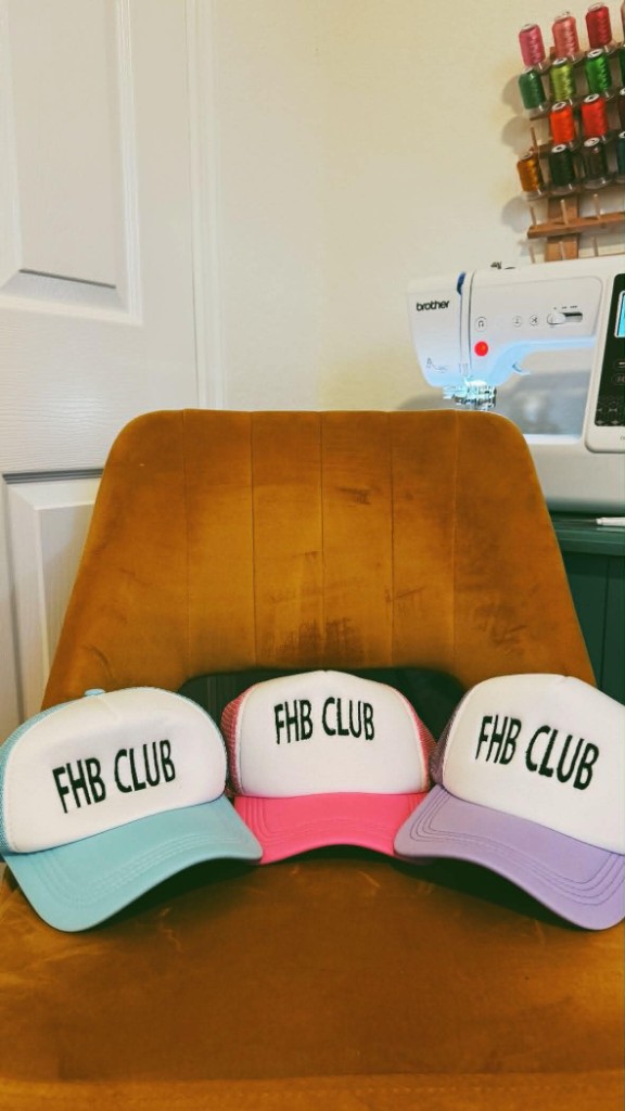 Three trucker hats in blue, pink, and purple embroidered with FHB CLUB